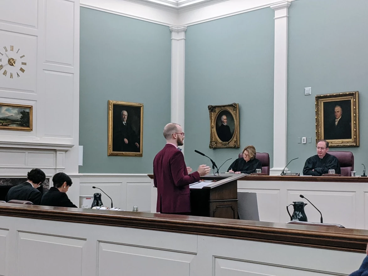 A man stands before judges in a court room